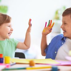 Two children with painted hands laughing while crafting