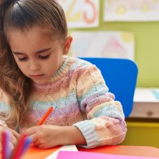 Young girl coloring at classroom table