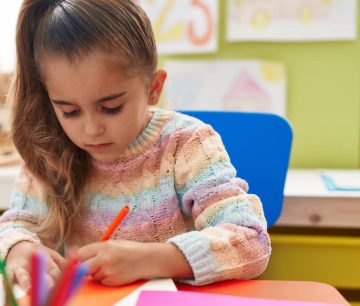 Young girl coloring at classroom table