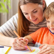 Woman and young boy drawing together at table
