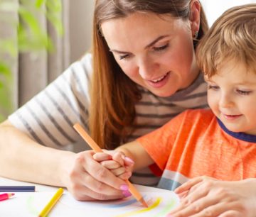 Woman and young boy drawing together at table
