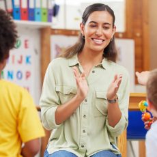 Smiling teacher clapping with young children