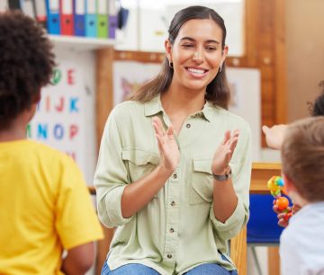Smiling teacher clapping with young children