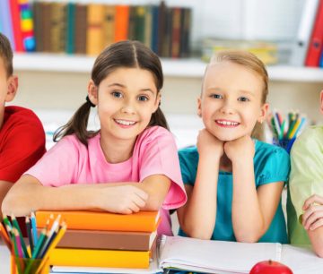 Four smiling schoolchildren at desk with books