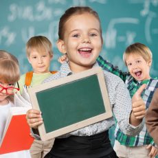 Group of smiling schoolchildren with books and chalkboard