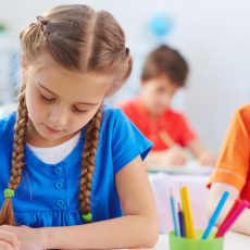 Girls writing with colored pencils in classroom