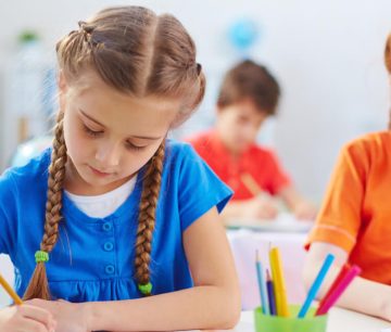 Girls writing with colored pencils in classroom