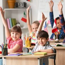 Elementary students raising hands in classroom