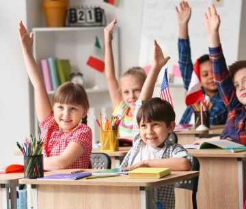 Elementary students raising hands in classroom
