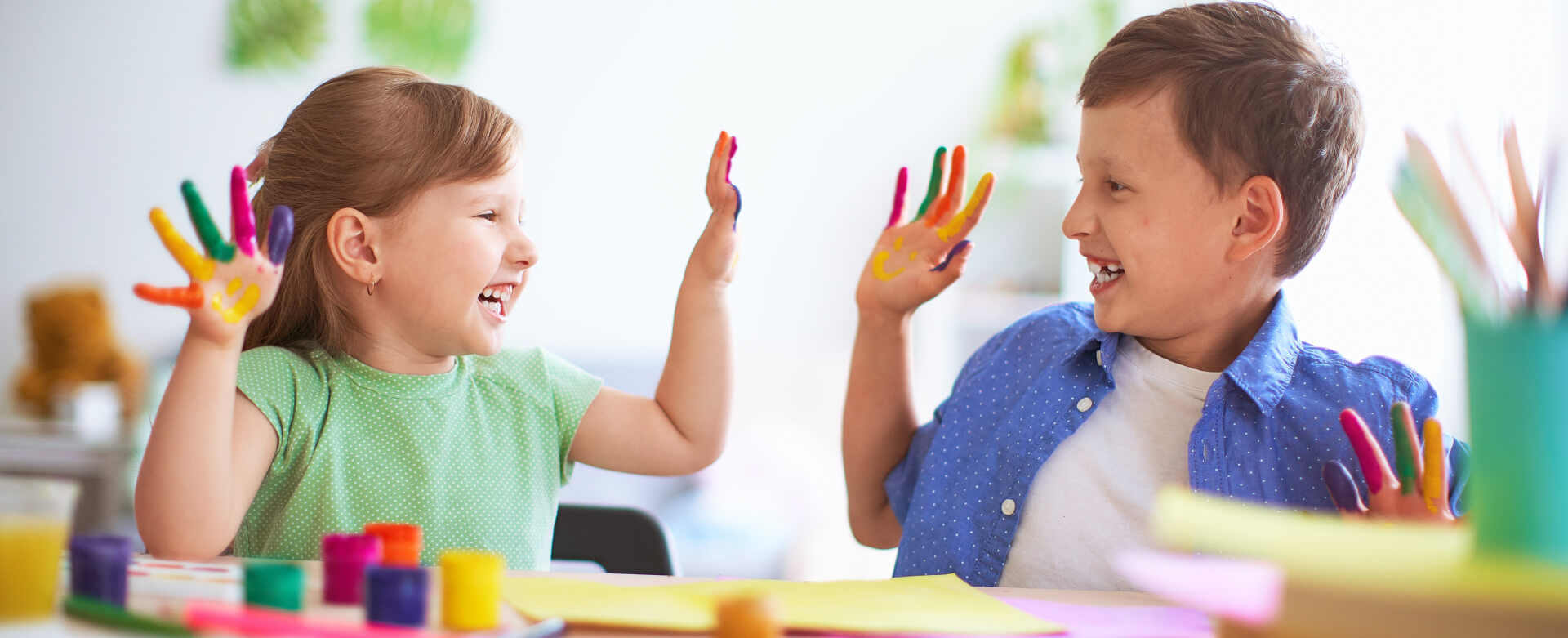 Two children with colorful painted hands high-fiving