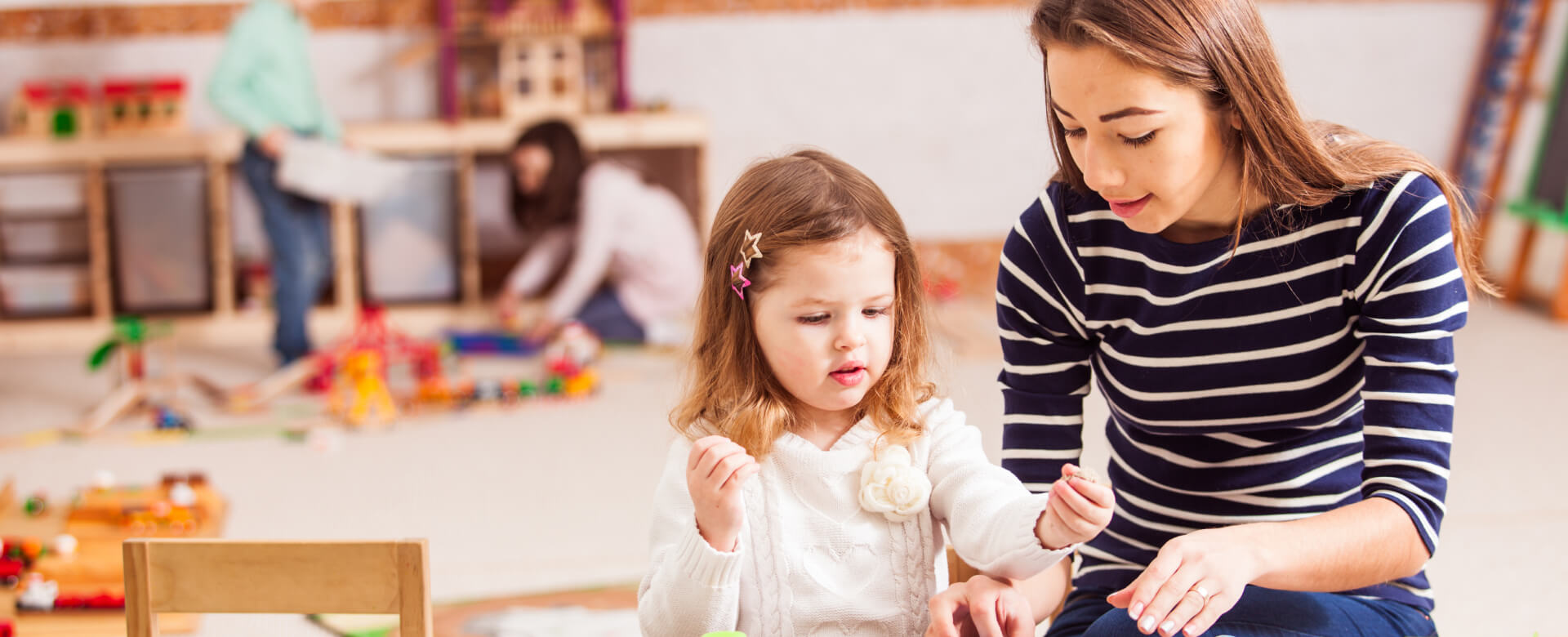 Adult and child playing in preschool classroom